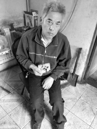 老人手拿爱子照片,悲痛不已 老人手拿爱子照片,悲痛不已